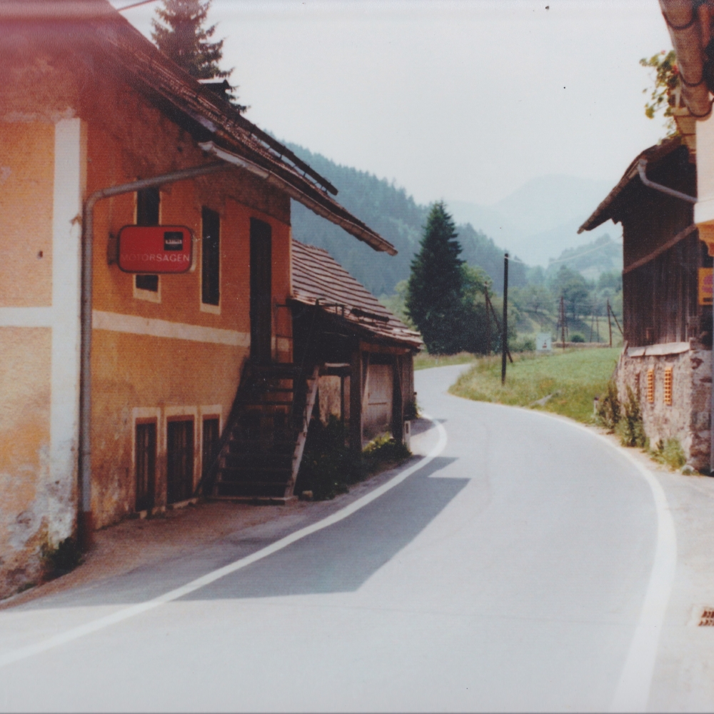Fotografie 1960er Jahre. Ansicht der Straße vor der Verbreiterung und dem daraus folgenden Abriss der Werkstatt samt Schmiede und dem alten Wohnhaus.