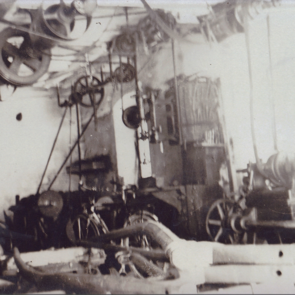 Fotografie um 1945. Einblick in die Werkstatt. Lederriemen auf zahlreichen Antriebswellen befinden sich an der Decke.